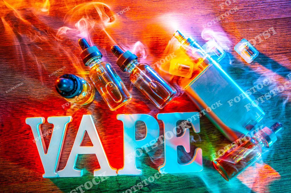 Стильное изображение электронной сигареты VAPE с густым паром и жидкостью для вейпинга. На фотографии представлены современные vape-устройства, жидкости для электронных сигарет и элементы современной vape-культуры, создающие атмосферу технологичного lifestyle и альтернативного курения. Пар, минималистичная композиция и современный дизайн делают изображение идеальным для рекламы vape shop, интернет-магазинов электронных сигарет и аксессуаров для парения. Фотография отлично подходит для маркетинговых материалов, баннеров, публикаций о вейпинге и продвижения товаров для современных вейперов.
